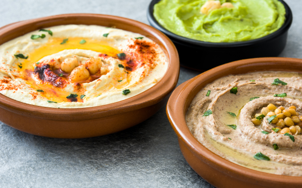 Different hummus bowls on gray stone