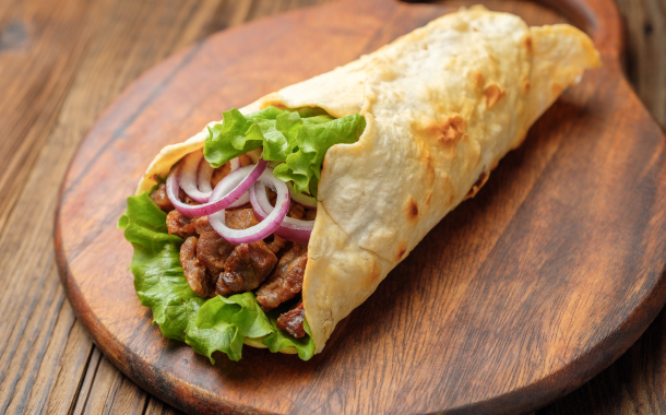 Shawarma with meat, onions, salad lies on a dark old wooden table.