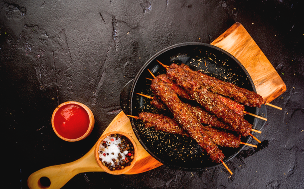 Shish kebab on a stick with ketchup, spices and tomatoes